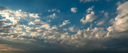 Bulky clouds illuminated by the setting sun. The contrast between light and shadow adds drama,...