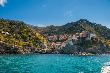 Cinque Terre, the seaside village with colorful buildings, fortress towers, and bell tower, nestled between terraced cliffs above the blue waters of the Ligurian Sea.の写真素材