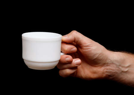 White cup in hand on a black backgroundの写真素材