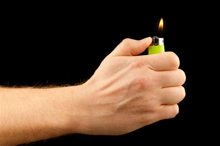 Lighter in hand on a black backgroundの写真素材