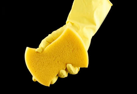 A hand in a yellow cleaner glove holds a sponge