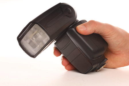 Speedlight flash in hand on a white backgroundの写真素材