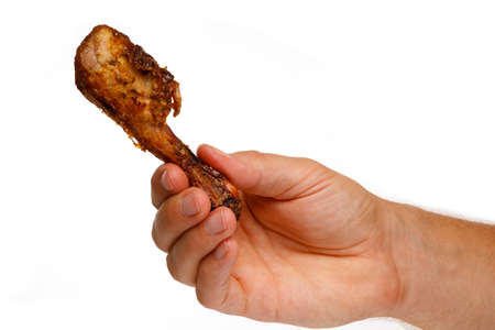 Piece of roasted chicken in hands on a white backgroundの写真素材