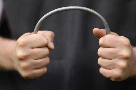 Strong hands bend a metal rodの写真素材