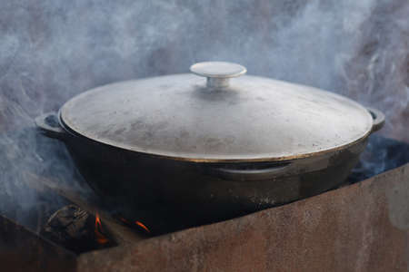Food is prepared in a cauldron on the fireの写真素材