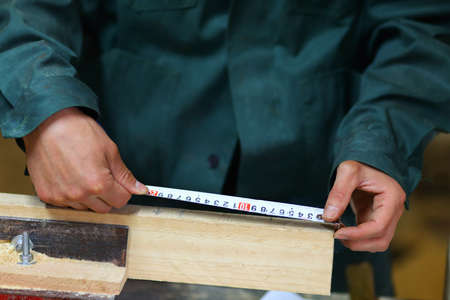 The carpenter measures the dimensions of the object with a tapeの写真素材