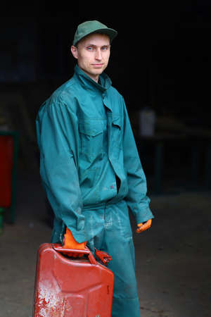 A young worker in uniform holds a canister of gasolineの写真素材