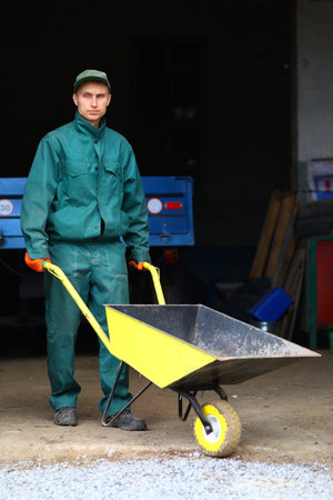 A young worker holds a wheelbarrowの写真素材
