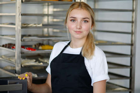 Beautiful blonde baker girl in a mini bakeryの写真素材
