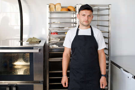 Young baker worker in a bakery in uniformの写真素材