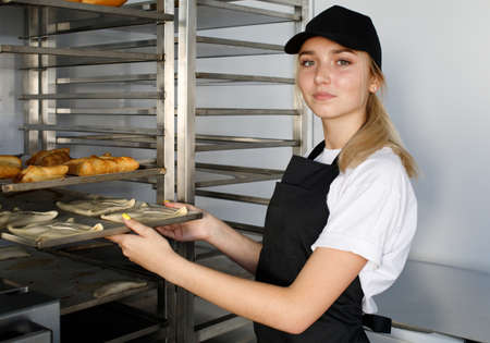 Beautiful blonde baker girl in a mini bakery