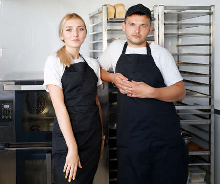 Beautiful young workers bakers Beautiful young workers bakers boy and girl in a mini bakery and girl...