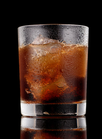 Soft drink in a glass with ice black backgroundの写真素材