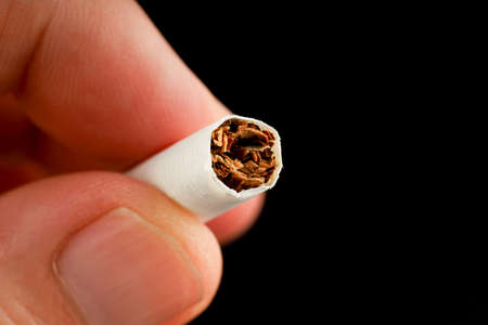 Hand holds a cigarette on a dark backgroundの写真素材