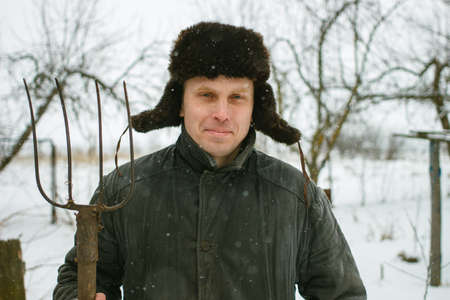 Peasant with pitchfork in winterの写真素材