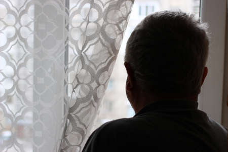 An old man looks out the windowの写真素材