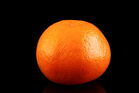 Whole unpeeled useful fruit tangerine close-up on a black backgroundの写真素材
