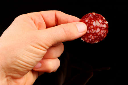 Red sausage in hand on black backgroundの写真素材