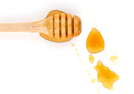 Honey dripping from a wooden dipper on a white background isolateの写真素材