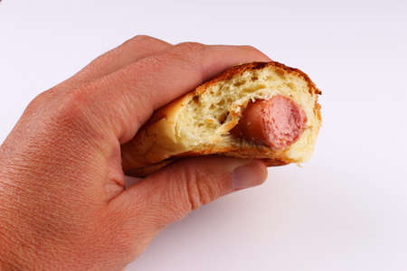 Scented bun with sausage in hand on a white backgroundの写真素材