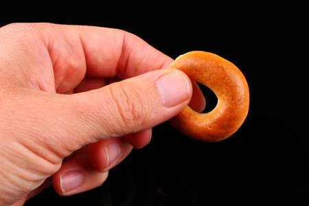 One bagel in hand on black backgroundの写真素材