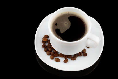 Coffee drink in a white cup and grains on a black backgroundの写真素材