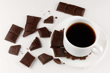 Coffee in a cup and pieces of chocolate on a white backgroundの写真素材