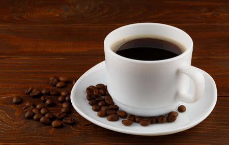 Coffee drink and beans in a cup on a wooden backgroundの写真素材