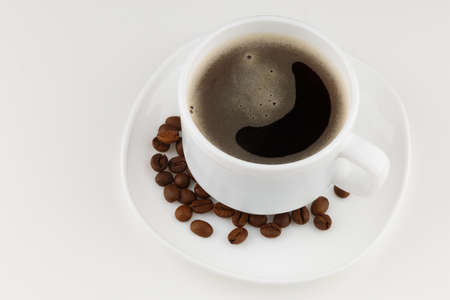 Coffee drink in a white cup and grains on a white backgroundの写真素材