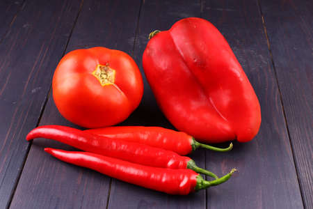 Red vegetables, peppers and tomatoes on a wooden backgroundの写真素材