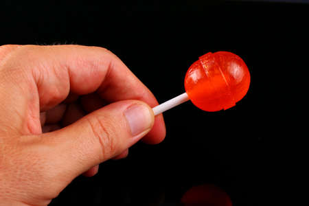 Caramel candy on a stick in handsの写真素材