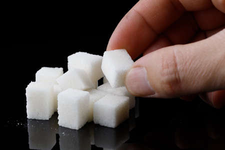 Pieces of sugar in hand on a black backgroundの写真素材