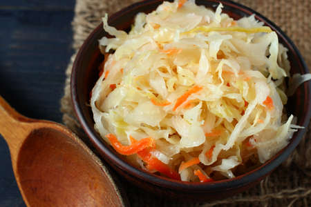Sauerkraut salad in a plate and a wooden spoonの写真素材