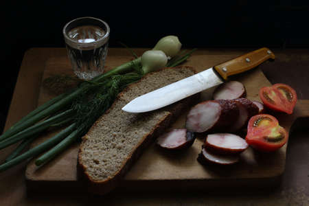 Simple rustic food. Sausage, tomato, knife and bread.の写真素材