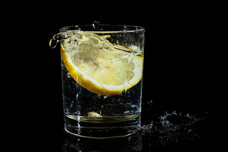 Water with lemon in a glass on a black background.の写真素材