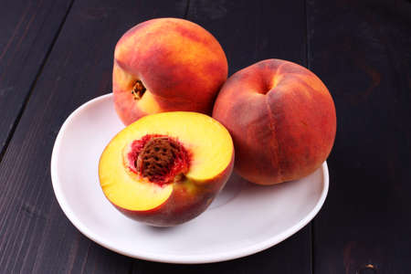 Peach in a plate on a dark wooden backgroundの写真素材