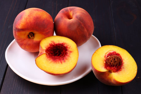 Peach in a plate on a dark wooden backgroundの写真素材