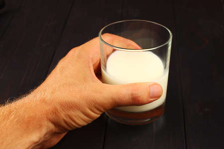 glass of milk on a dark background in handの写真素材