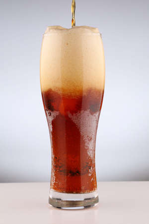 Glass with light brown beer on a white background