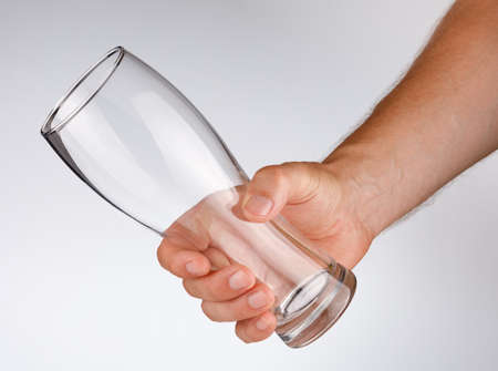Empty glass in his hand on a white backgroundの写真素材