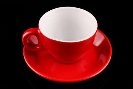 Empty red cup and saucer on a black background