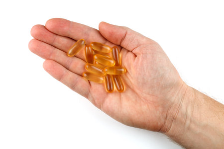 Omega 3 gelatin capsules in the palm on a white background isolateの写真素材