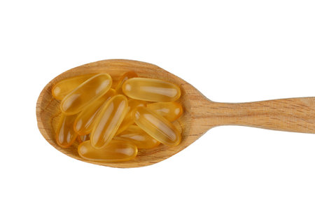 Omega 3 gelatin capsules in a wooden spoon on a white backgroundの写真素材