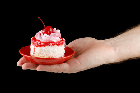 Cake with cream and cherry on a red saucer. Homemade cupcake iced with a cherry on topの写真素材