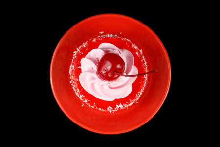 Cake with cream and cherry on a red saucer, top viewの写真素材