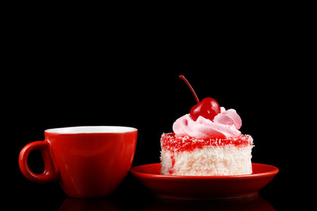 Cake with cream and cherry on a red saucer and coffeeの写真素材