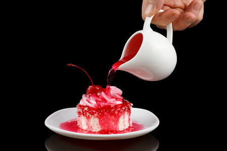 The cook pours cherry sauce on a cupcake or cake.の写真素材