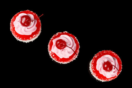 Cupcakes with cream and cherry, top view on blackの写真素材