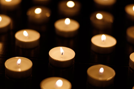 Small candles burning on a dark background. Lights of candlesの写真素材