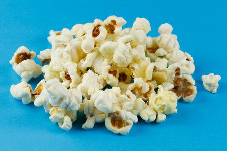 A pile of popcorn on a blue background. heap of popcornの写真素材